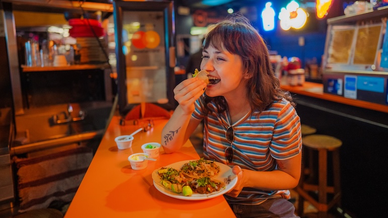 Woman sitting at a restauant laughing and eating.