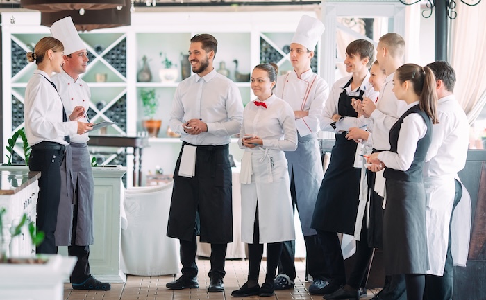 Image of restaurant workers having a conversation with the head chef about the best non-slip shoes for restaurant workers.
