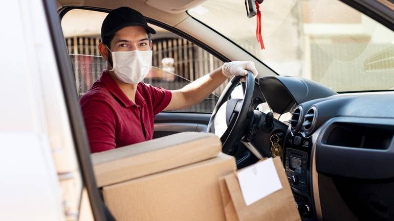 Delivery driver with food delivery on front seat of car