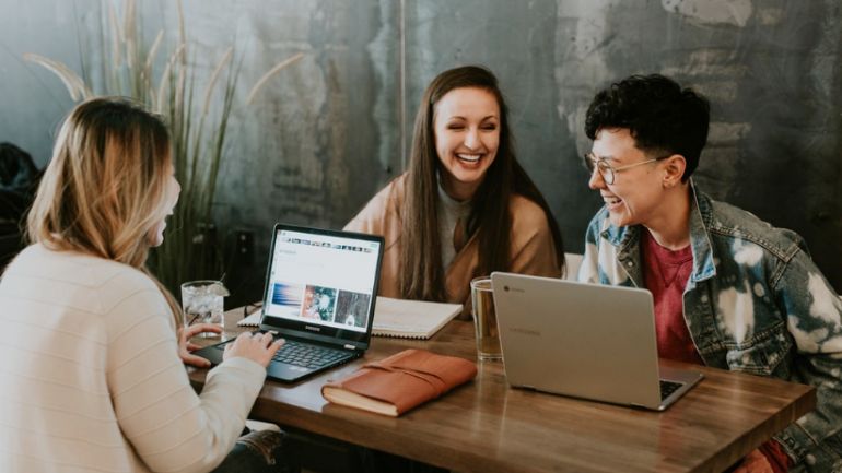 three customers at a cafe table using wifi on their laptops