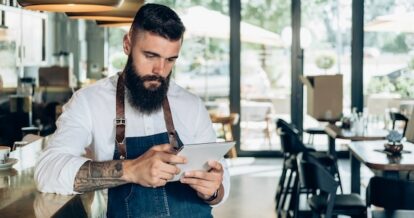 restaurant staff member looking down using mobile tablet.